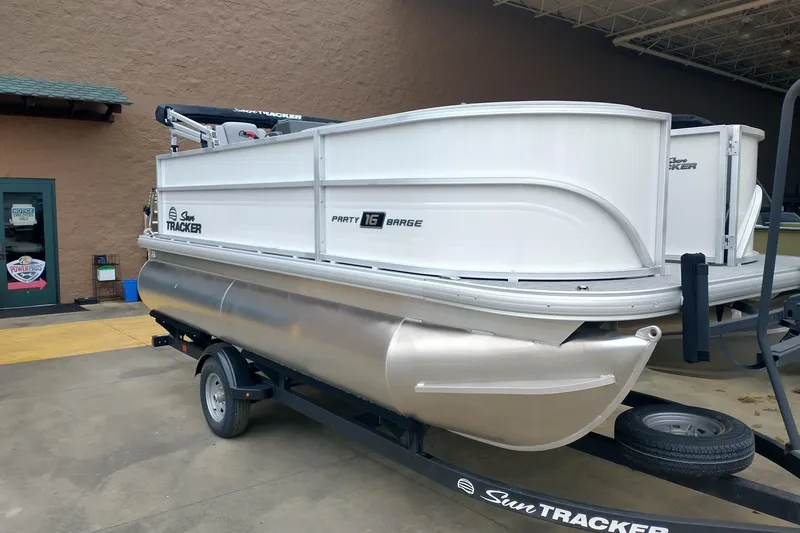 The Image of 2026 Sun Tracker Party Barge 16 DLX pontoon boat on trailer, parked outdoors. - 0