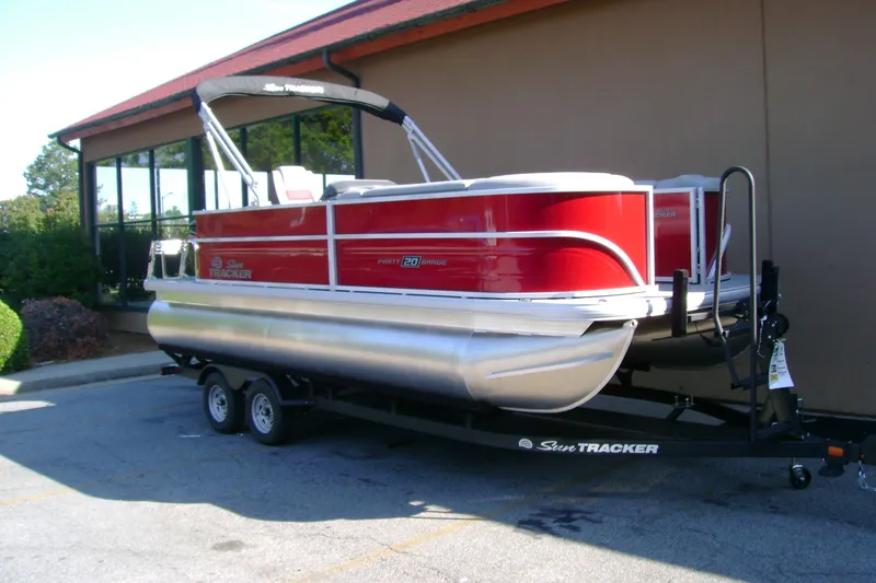 Slide: The Image of 2026 Sun Tracker Party Barge 20 DLX pontoon boat on trailer, parked outdoors. - 1