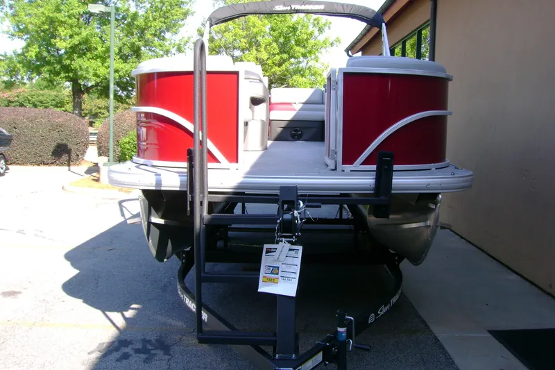Slide: The Image of 2026 Sun Tracker Party Barge 20 DLX pontoon boat with red exterior, parked on a trailer. - 2