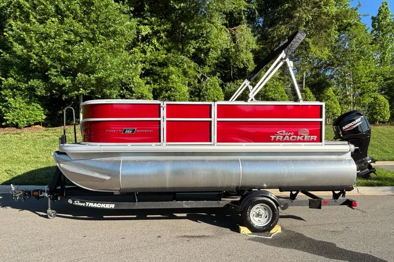 The Image of 2026 Sun Tracker Party Barge 16 DLX pontoon boat on trailer, parked outdoors. - 0