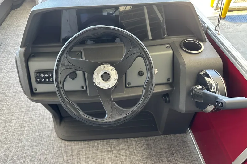Slide: The Image of 2026 Sun Tracker Party Barge 18 DLX steering console with controls and cup holder. - 24
