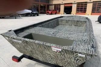 Slide: The Image of 2026 Tracker Grizzly 1648 Utility boat with camouflage design in outdoor showroom. - 6