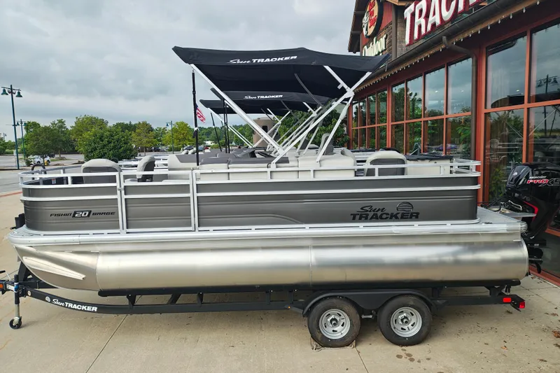 The Image of 2026 Sun Tracker Fishin' Barge 20 DLX pontoon boat displayed outside a dealership. - 1