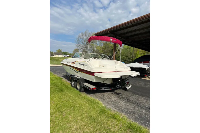Slide: The Image of 2005 Hurricane SunDeck 187 IO boat with red canopy on trailer, parked outdoors. - 3
