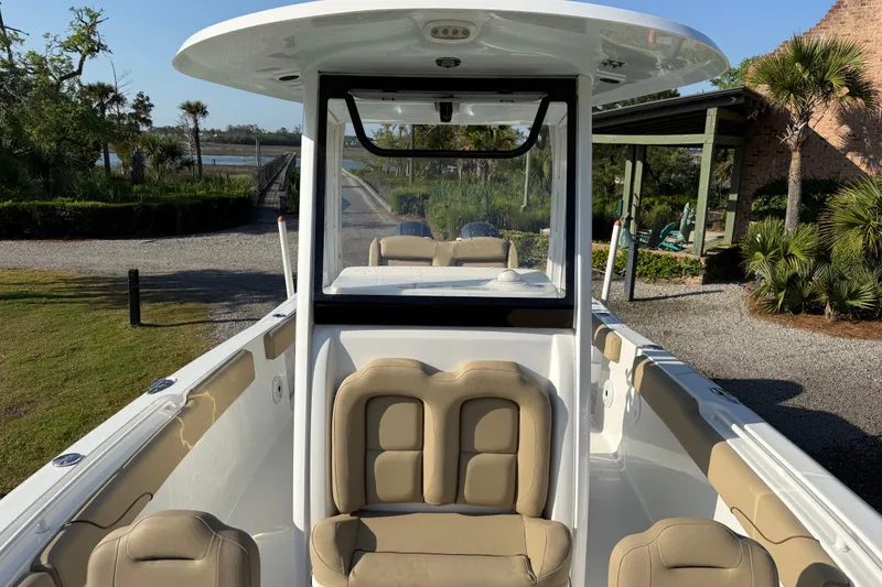 Slide: The Image of 2017 Sea Hunt Gamefish 25 boat with beige seating, docked near lush greenery. - 26