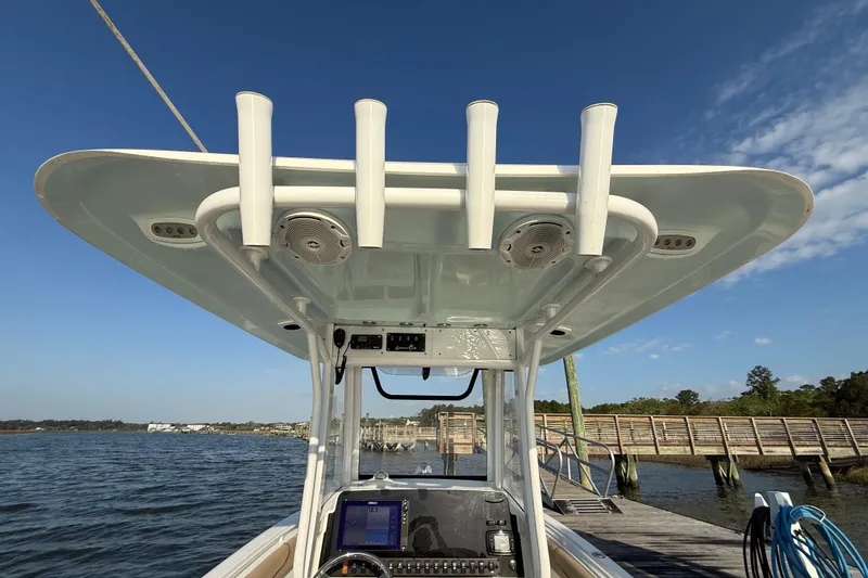 Slide: The Image of 2017 Sea Hunt Gamefish 25 boat console with rod holders and electronics, docked by a wooden pier. - 35