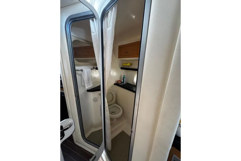 Slide: The Image of 2009 Rinker 340 Express Cruiser bathroom interior with toilet, sink, and storage cabinets. - 19