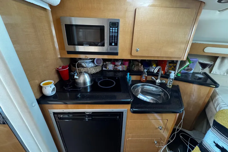 Slide: The Image of 2009 Rinker 340 Express Cruiser kitchen with microwave, sink, and stove. - 25