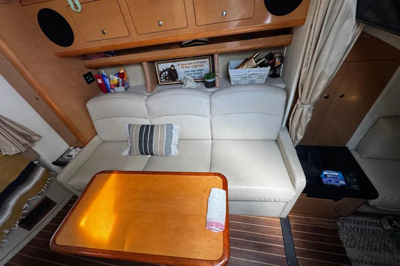 Slide: The Image of Interior of 2009 Rinker 340 Express Cruiser with white leather seating and wooden table. - 26