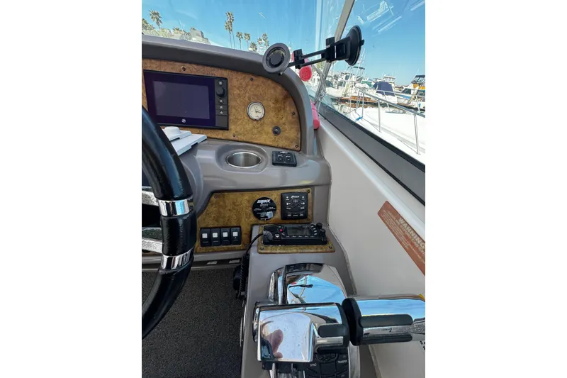 Slide: The Image of 2009 Rinker 340 Express Cruiser helm with controls, gauges, and steering wheel. - 29