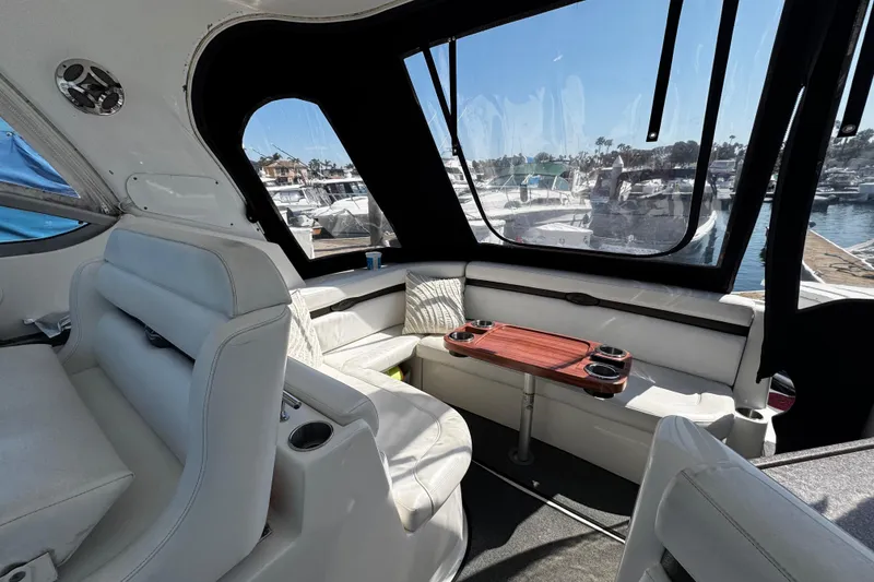 Slide: The Image of Interior of 2009 Rinker 340 Express Cruiser with white seating and marina view. - 37