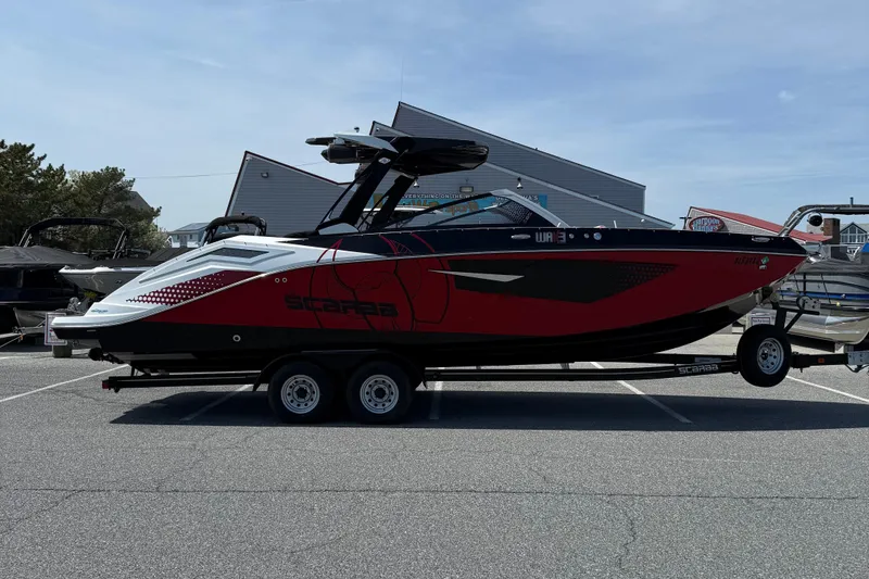 The Image of 2022 Scarab 285 ID boat on trailer, red and black design, parked outdoors. - 1