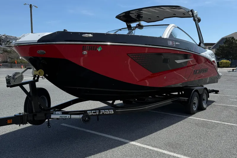Slide: The Image of 2022 Scarab 285 ID boat on trailer in parking lot, red and black design. - 4