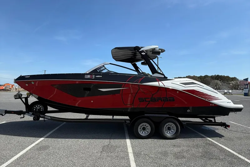 Slide: The Image of 2022 Scarab 285 ID boat in red and black on a trailer, parked outdoors. - 5