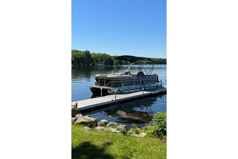 Slide: The Image of 2024 Sun Tracker Party Barge 22 DLX pontoon boat docked on a serene lake. - 4