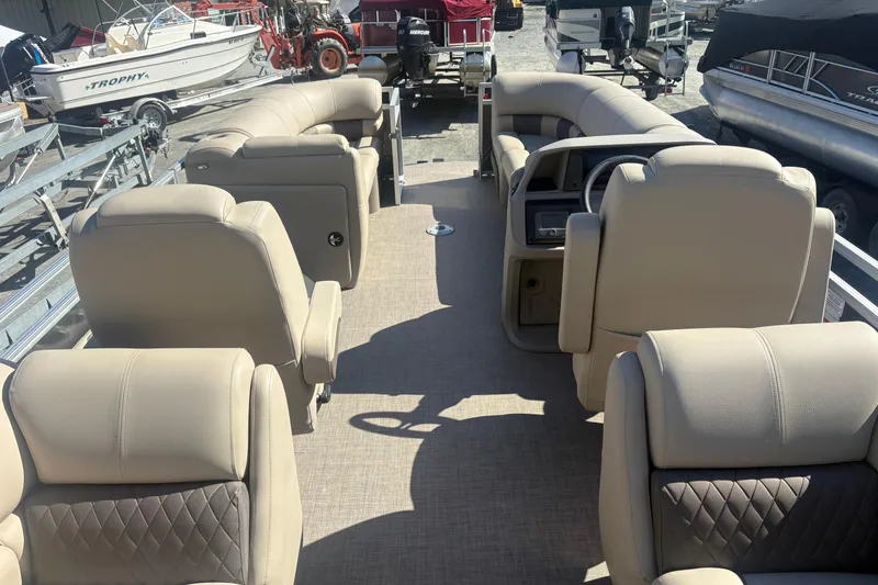 Slide: The Image of 2024 Sun Tracker Party Barge 22 DLX interior with beige seating and steering console. - 7