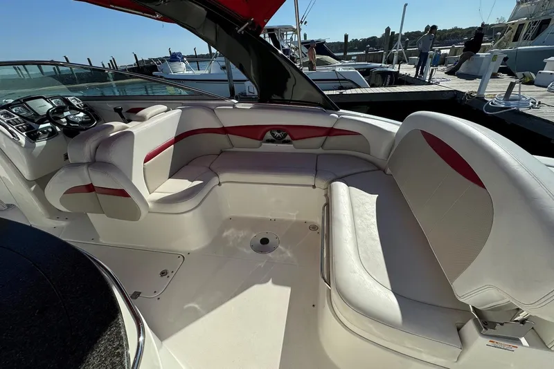 Slide: The Image of 2012 Chaparral 2870 SSX boat interior with white and red seating at a marina. - 3