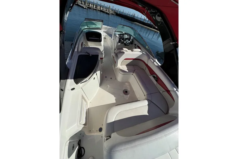 Slide: The Image of 2012 Chaparral 2870 SSX boat interior with white seating and red accents, docked by water. - 4