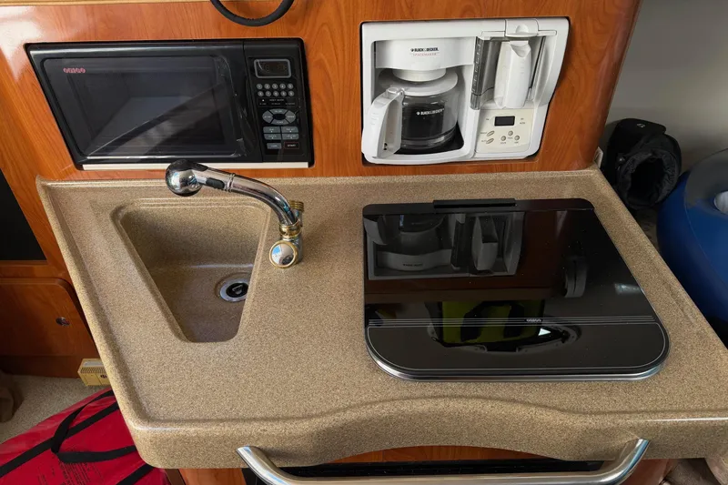 Slide: The Image of 2003 Wellcraft 2600 Martinique kitchenette with sink, microwave, coffee maker, and stove. - 6