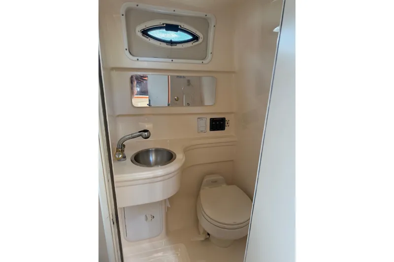 Slide: The Image of 2003 Wellcraft 2600 Martinique boat bathroom with sink, toilet, and porthole window. - 9