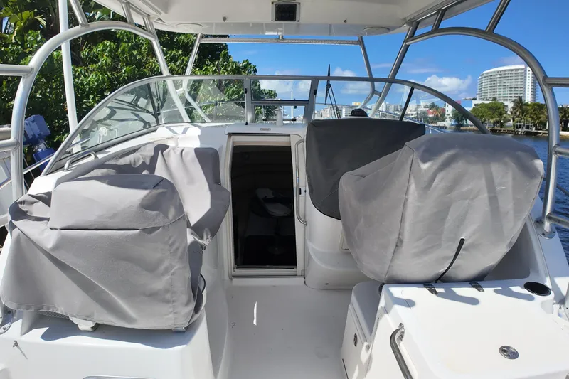 Slide: The Image of 2005 Boston Whaler 305 Conquest boat interior with covered seats and open cabin door. - 14