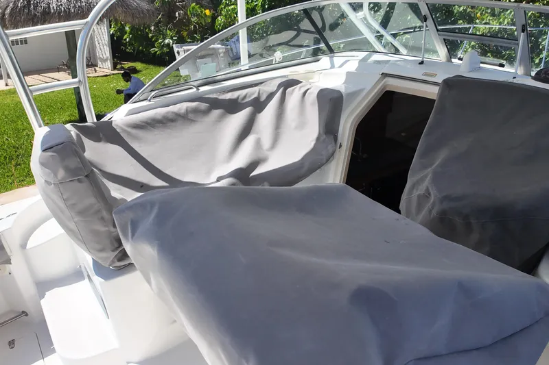 Slide: The Image of 2005 Boston Whaler 305 Conquest boat with covered seating and windshield, docked outdoors. - 16