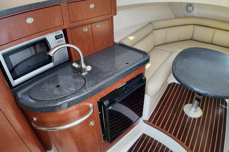 Slide: The Image of 2005 Boston Whaler 305 Conquest interior with kitchenette, microwave, sink, and seating area. - 17