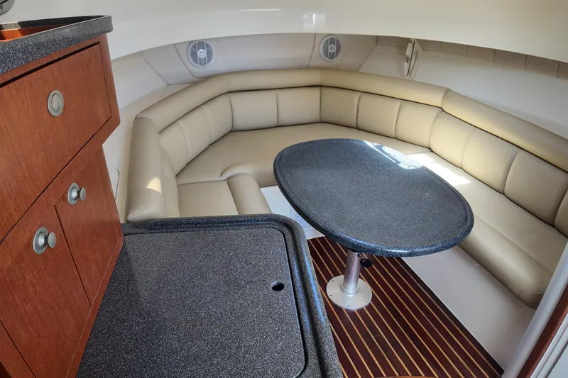 Slide: The Image of 2005 Boston Whaler 305 Conquest cabin interior with cushioned seating and table. - 18