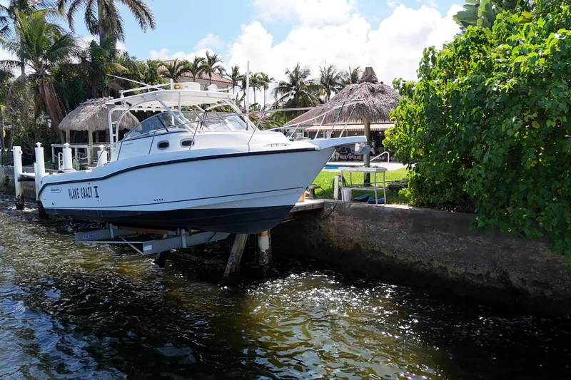 Slide: The Image of 2005 Boston Whaler 305 Conquest boat docked near tropical waterfront. - 2