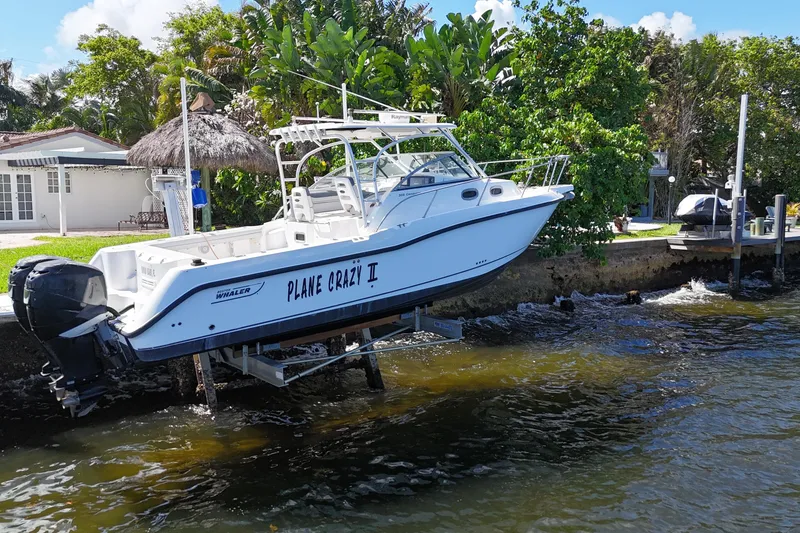 Slide: The Image of 2005 Boston Whaler 305 Conquest boat named "Plane Crazy II" docked by a waterfront home. - 4