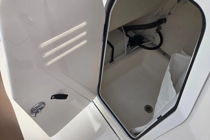 Slide: The Image of Open storage compartment on 2024 Pioneer 202 Islander boat, showing interior details and drainage. - 11