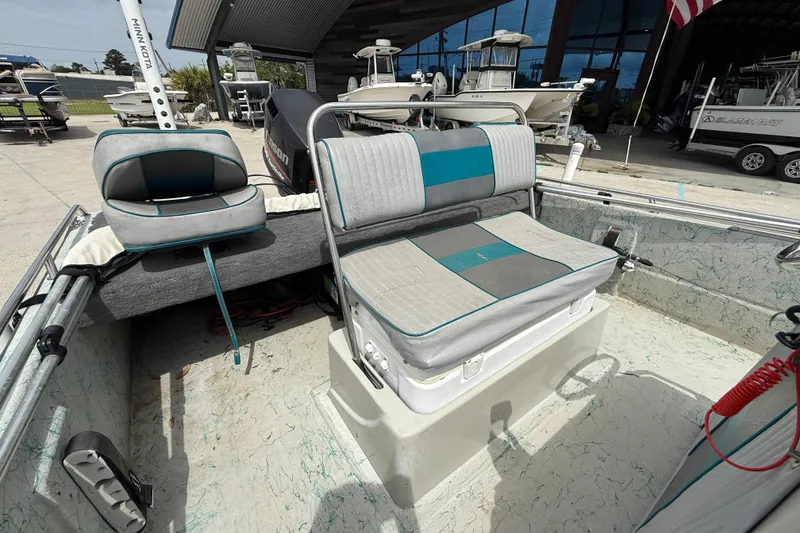 Slide: The Image of 1998 Predator 18ft CC boat interior with cushioned seating and motor, docked outdoors. - 10