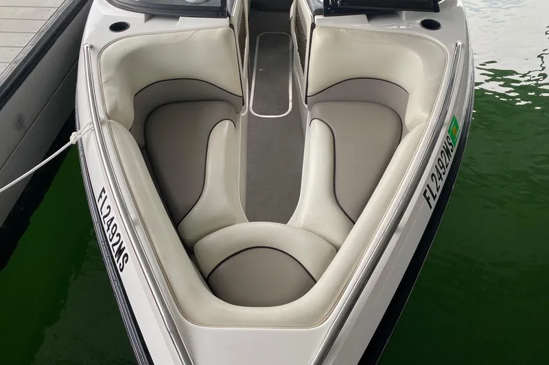 Slide: The Image of 2004 Malibu Wakesetter 21 XTi boat with white interior, docked on green water. - 2