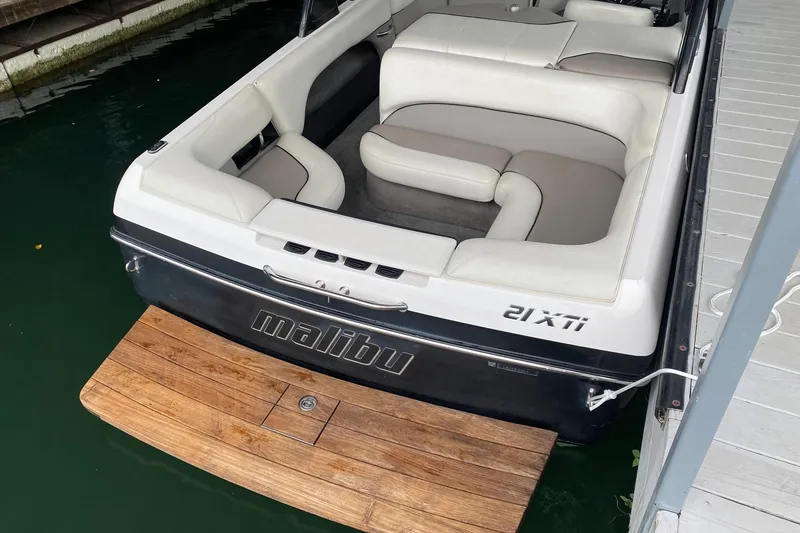 Slide: The Image of 2004 Malibu Wakesetter 21 XTi boat with white seating and wooden swim platform. - 3