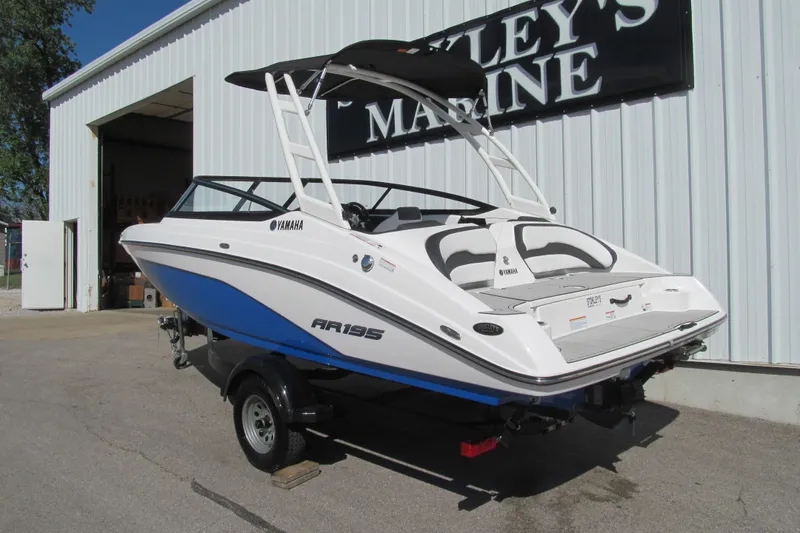 Slide: The Image of 2024 Yamaha Boats AR195 in white and blue, parked outside a marine dealership. - 3