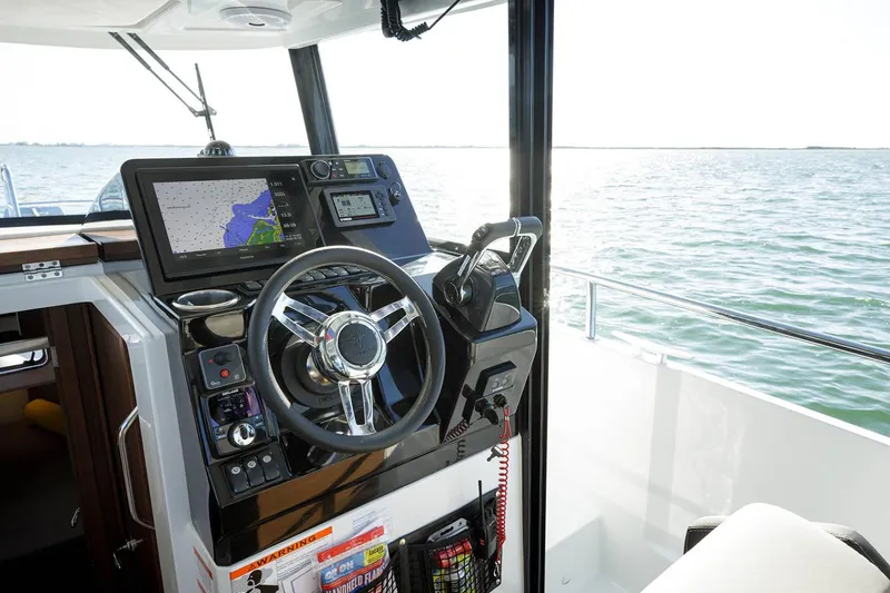 Slide: The Image of 2024 Jeanneau NC Sport 895 interior with helm, seat, microwave, and cabinetry. - 10