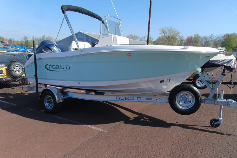 The Image of 2025 Robalo R180 Center Console boat on trailer, parked outdoors. - 1