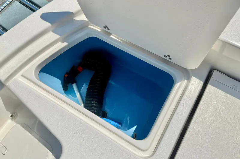 Slide: The Image of Storage compartment on 2026 Carolina Skiff 22 Ultra Elite boat, featuring a hose and accessories. - 34