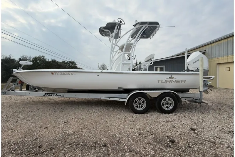Slide: The Image of 2023 Turner Boatworks 2500VS on trailer, white hull, dual engines, parked outdoors. - 16