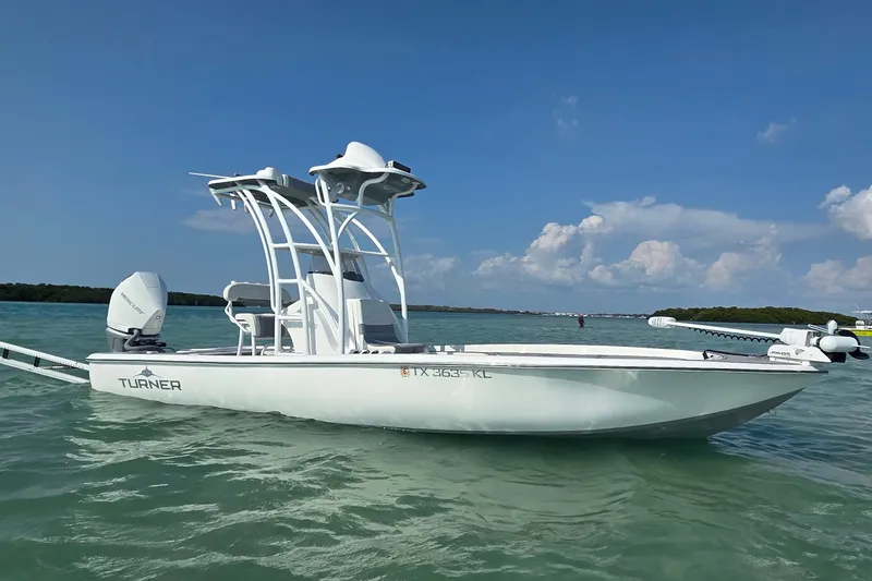 Slide: The Image of 2023 Turner Boatworks 2500VS on calm water under clear blue sky. - 2