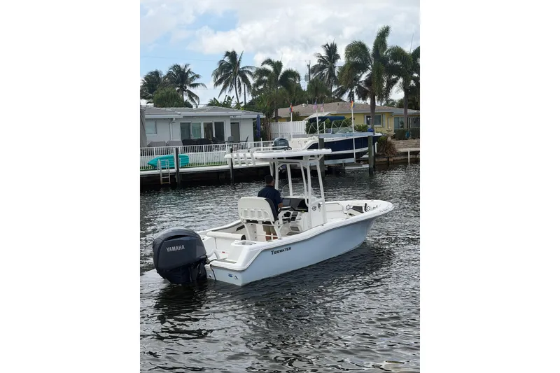 The Image of 2025 Tidewater 210 CC Adventure boat on water, with Yamaha engine, near waterfront homes and palm trees. - 0