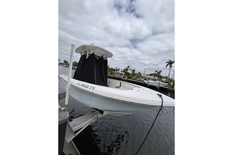 The Image of 2025 Tidewater 210 CC Adventure boat docked by a waterfront under cloudy skies. - 2