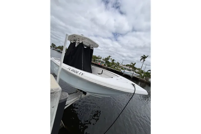Slide: The Image of 2025 Tidewater 210 CC Adventure boat docked by a waterfront, under cloudy skies. - 4