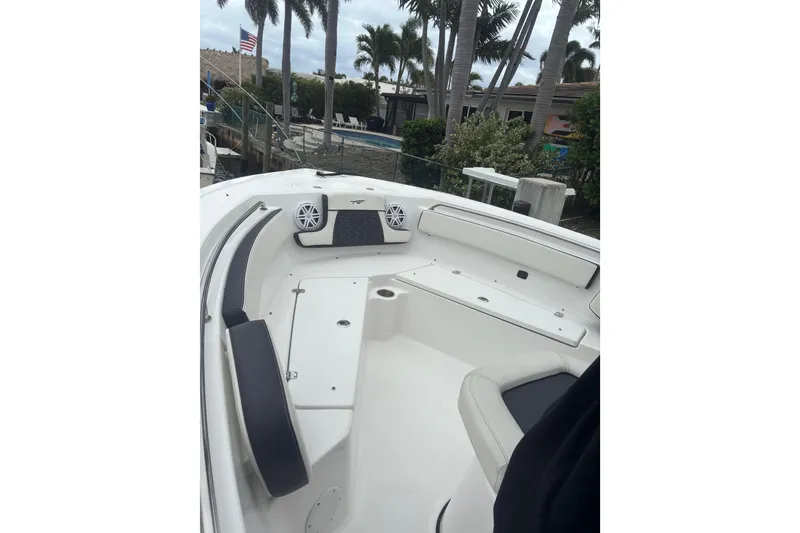 Slide: The Image of 2025 Tidewater 210 CC Adventure boat interior with seating and speakers, surrounded by palm trees. - 9