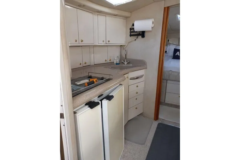 Slide: The Image of Interior of 1997 Sea Ray 370 Express Cruiser, featuring compact kitchen with cabinets and appliances. - 22