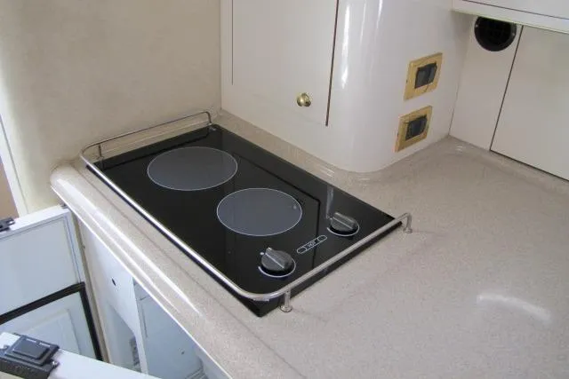 Slide: The Image of 1997 Sea Ray 370 Express Cruiser kitchen with stove, sink, and storage cabinets. - 24