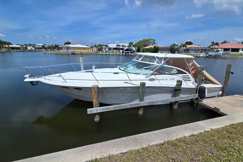 Slide: The Image of 1997 Sea Ray 370 Express Cruiser docked in a serene waterfront setting. - 69