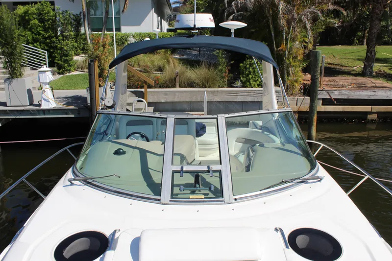 Slide: The Image of 2005 Sea Ray Sundancer 320 cockpit with white seating and steering controls, docked by the water. - 11