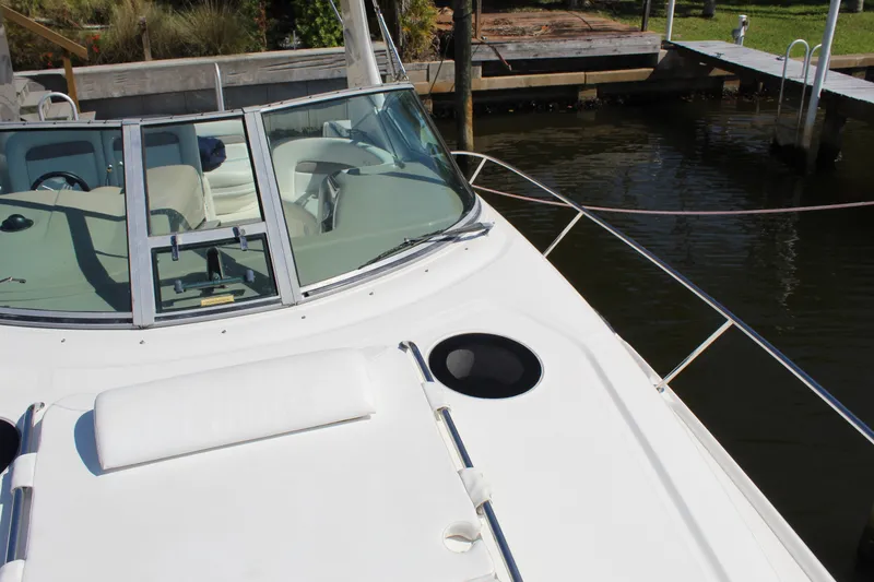 Slide: The Image of 2005 Sea Ray Sundancer 320 cockpit with canopy, docked in a marina under clear skies. - 12