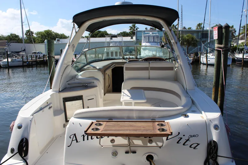 Slide: The Image of 2005 Sea Ray Sundancer 320 boat interior with seating and table, docked by the water. - 24